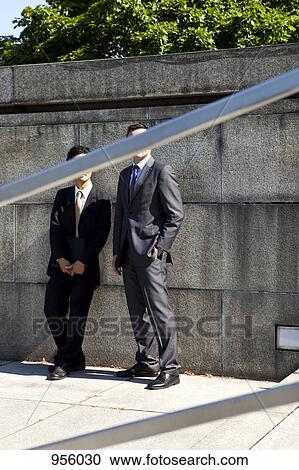 Two businessmen, faces obscured by railing View Large Photo Image Stock Image - Two businessmen, faces obscured by railing. Fotosearch