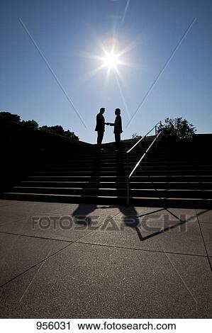 Two businessmen shaking hands, outdoors, silhouette View Large Photo Image Stock Image - Two businessmen shaking hands, outdoors, silhouette. Fotosearch