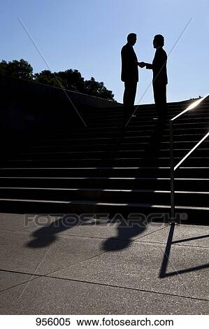 Two businessmen shaking hands, outdoors, silhouette View Large Photo Image Stock Photography - Two businessmen shaking hands, outdoors, silhouette. Fotosearch