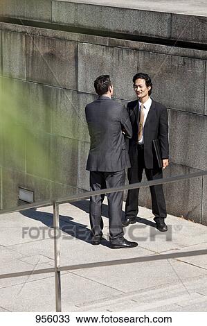Two businessmen talking, outdoors View Large Photo Image Stock Image - Two businessmen talking, outdoors. Fotosearch