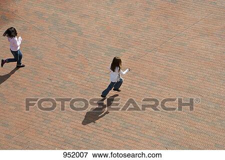 Stock Photo - Two girl skipping through an urban plaza. Fotosearch