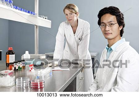 Two lab technicians in a laboratory, looking at camera View Large Photo Image Stock Image - Two lab technicians in a laboratory, looking at camera. Fotosearch