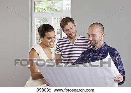 Stock Photography - A building contractor showing blueprints to a young couple. Fotosearch