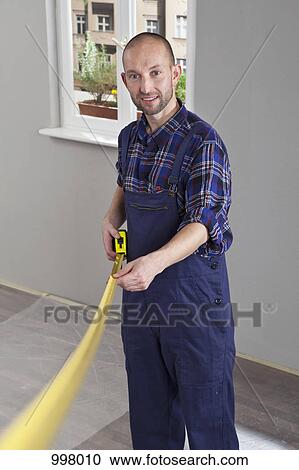 Stock Image - A building contractor using a tape measure. Fotosearch