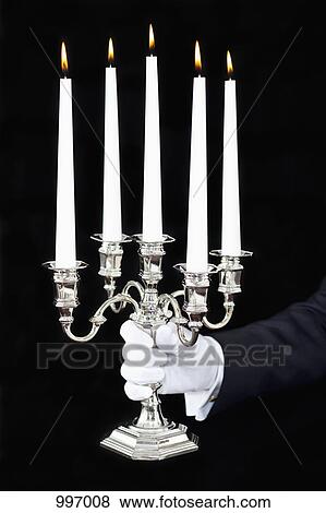 Stock Photo - A butler holding a candelabra with lit candles, focus on hand. Fotosearch