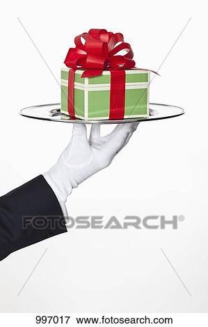 A butler presenting a gift on a silver tray, focus on hand View Large Photo Image Stock Photo - A butler presenting a gift on a silver tray, focus on hand. Fotosearch