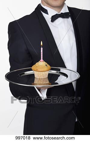 A butler presenting a muffin with a lit birthday candle on a silver tray, focus on hand View Large Photo Image Stock Photo - A butler presenting a muffin with a lit birthday candle on a silver tray, focus on hand. Fotosearch