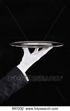 Stock Image - A butler presenting an empty silver tray, focus on hand. Fotosearch