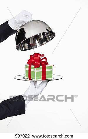 A butler taking the lid off a domed tray, revealing a gift, focus on hands View Large Photo Image Stock Image - A butler taking the lid off a domed tray, revealing a gift, focus on hands. Fotosearch