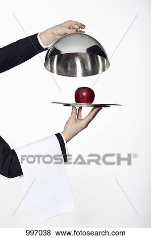 A butler taking the lid off a domed tray, revealing a red apple, focus on hands View Large Photo Image Stock Photo - A butler taking the lid off a domed tray, revealing a red apple, focus on hands. Fotosearch