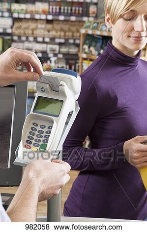 A cashier putting a card into a credit card machine at the supermarket View Large Photo Image Stock Photo - A cashier putting a card into a credit card machine at the supermarket. Fotosearch