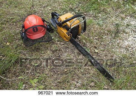 A chainsaw and safety helmet lying on the grass View Large Photo Image Stock Image - A chainsaw and safety helmet lying on the grass. Fotosearch