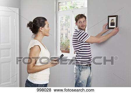 A couple hanging a picture frame in their new home View Large Photo Image Stock Photo - A couple hanging a picture frame in their new home. Fotosearch