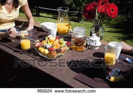A couple having breakfast together on a backyard deck, midsection View Large Photo Image Picture - A couple having breakfast together on a backyard deck, midsection. Fotosearch