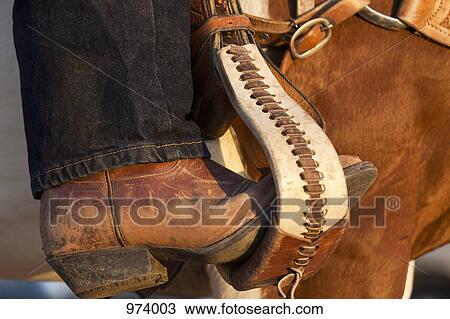 Stock Image - A cowboy boot in a horse stirrup, detail. Fotosearch