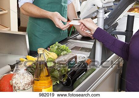 A customer handing a cashier a credit card at the supermarket View Large Photo Image Stock Photo - A customer handing a cashier a credit card at the supermarket. Fotosearch