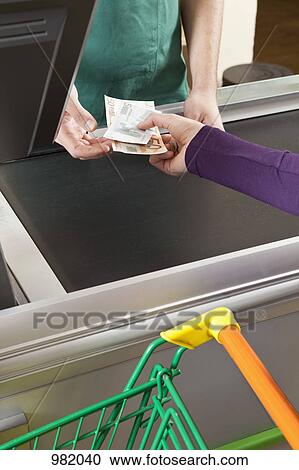 A customer handing a cashier cash at the supermarket View Large Photo Image Stock Image - A customer handing a cashier cash at the supermarket. Fotosearch