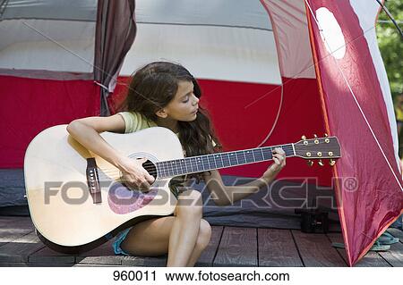 A girl playing an acoustic guitar next to a camping tent View Large Photo Image Stock Image - A girl playing an acoustic guitar next to a camping tent. Fotosearch