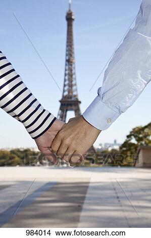 A man and woman holding hands in front of the Eiffel Tower, focus on hands View Large Photo Image Picture - A man and woman holding hands in front of the Eiffel Tower, focus on hands. Fotosearch