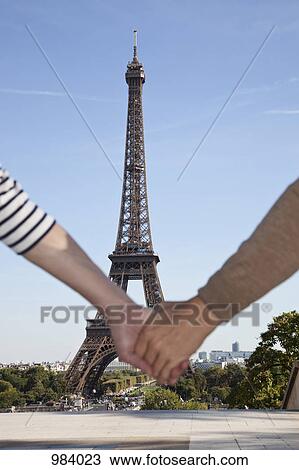 A man and woman holding hands in front of the Eiffel Tower, focus on background View Large Photo Image Stock Image - A man and woman holding hands in front of the Eiffel Tower, focus on background. Fotosearch
