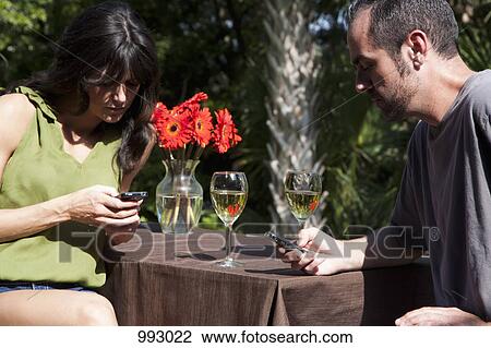 A man and woman text messaging on separate mobiles while on a backyard deck View Large Photo Image Stock Image - A man and woman text messaging on separate mobiles while on a backyard deck. Fotosearch