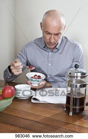 A man having breakfast and reading the newspaper View Large Photo Image Stock Photograph - A man having breakfast and reading the newspaper. Fotosearch