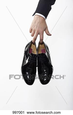 A man holding a pair of patent leather dress shoes, focus on hand View Large Photo Image Stock Image - A man holding a pair of patent leather dress shoes, focus on hand. Fotosearch