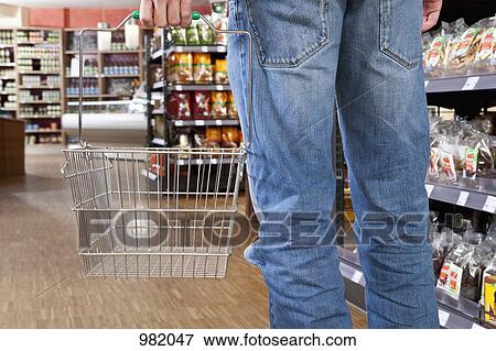 A man in a supermarket with an empty shopping basket, low section View Large Photo Image Stock Photo - A man in a supermarket with an empty shopping basket, low section. Fotosearch