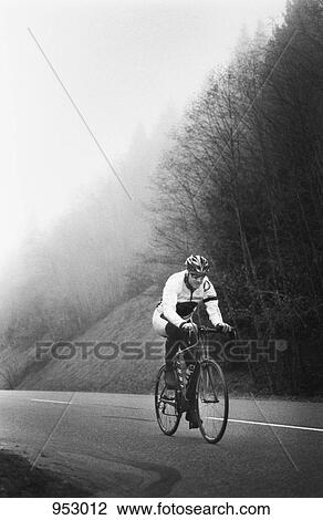 A man on a racing bicycle cycling up a mountain road View Large Photo Image Stock Image - A man on a racing bicycle cycling up a mountain road. Fotosearch