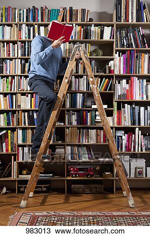 A man reading on a ladder in a home library View Large Photo Image Stock Image - A man reading on a ladder in a home library. Fotosearch