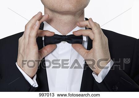 A man wearing a tuxedo adjusting his bow tie, focus on hands View Large Photo Image Stock Image - A man wearing a tuxedo adjusting his bow tie, focus on hands. Fotosearch