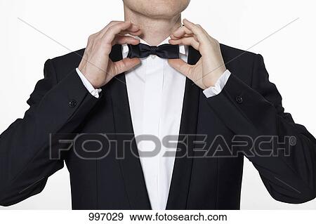 A man wearing a tuxedo adjusting his bow tie View Large Photo Image Stock Photo - A man wearing a tuxedo adjusting his bow tie. Fotosearch