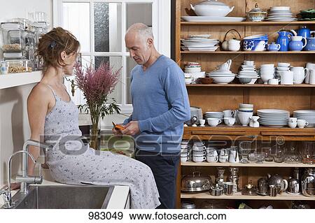 A mature couple having red wine together in their kitchen View Large Photo Image Stock Photo - A mature couple having red wine together in their kitchen. Fotosearch