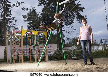 A mother pushing her daughter on a swing View Large Photo Image Stock Image - A mother pushing her daughter on a swing. Fotosearch