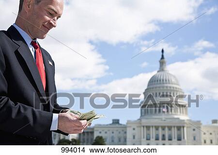 A politician counting money in front of the US Capitol Building View Large Photo Image Picture - A politician counting money in front of the US Capitol Building. Fotosearch