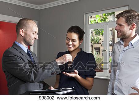 A real estate agent giving a couple the keys to their new home View Large Photo Image Stock Image - A real estate agent giving a couple the keys to their new home. Fotosearch