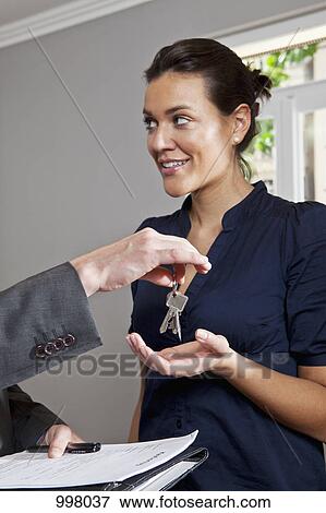 A real estate agent giving a woman the keys to her new home View Large Photo Image Stock Photo - A real estate agent giving a woman the keys to her new home. Fotosearch