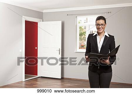 A real estate standing in an empty room holding a folder View Large Photo Image Stock Image - A real estate standing in an empty room holding a folder. Fotosearch
