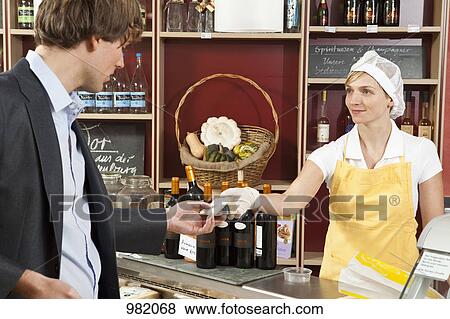 A sales clerk handing a customer a wedge of cheese View Large Photo Image Stock Photo - A sales clerk handing a customer a wedge of cheese. Fotosearch