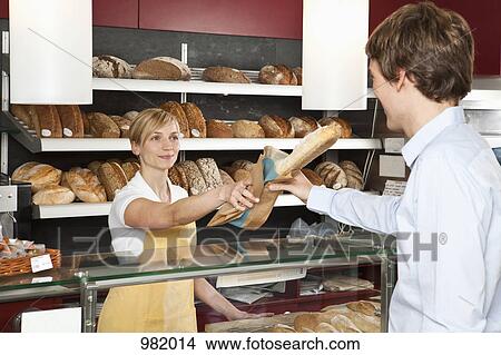 A sales clerk helping a customer at a bakery View Large Photo Image Picture - A sales clerk helping a customer at a bakery . Fotosearch