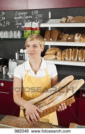 A sales clerk holding a basket of baguettes View Large Photo Image Stock Photo - A sales clerk holding a basket of baguettes. Fotosearch