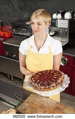 A sales clerk holding a fruit and nut tart View Large Photo Image Stock Image - A sales clerk holding a fruit and nut tart. Fotosearch