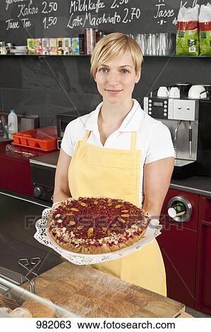 A sales clerk holding a fruit and nut tart View Large Photo Image Stock Image - A sales clerk holding a fruit and nut tart. Fotosearch