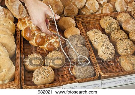 A sales clerk picking up a roll with tongs in a bakery, focus on hand View Large Photo Image Stock Image - A sales clerk picking up a roll with tongs in a bakery, focus on hand. Fotosearch