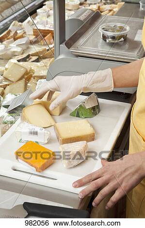 A sales clerk preparing wedges of cheese View Large Photo Image Stock Photograph - A sales clerk preparing wedges of cheese. Fotosearch