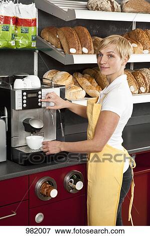 Stock Photo - A sales clerk using an espresso maker in a bakery cafe. Fotosearch