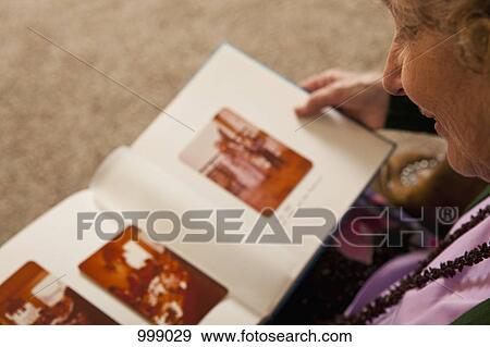 A senior woman looking at a photo album View Large Photo Image Stock Photo - A senior woman looking at a photo album. Fotosearch