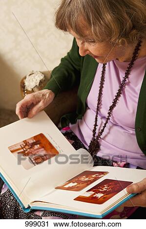 A senior woman looking through a photo album View Large Photo Image Stock Image - A senior woman looking through a photo album. Fotosearch