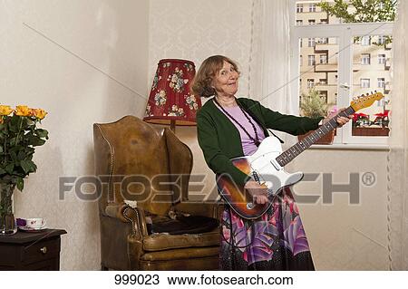 A senior woman playing an electric guitar View Large Photo Image Stock Image - A senior woman playing an electric guitar. Fotosearch