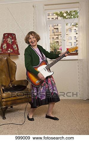 Stock Photo - A senior woman playing an electric guitar. Fotosearch